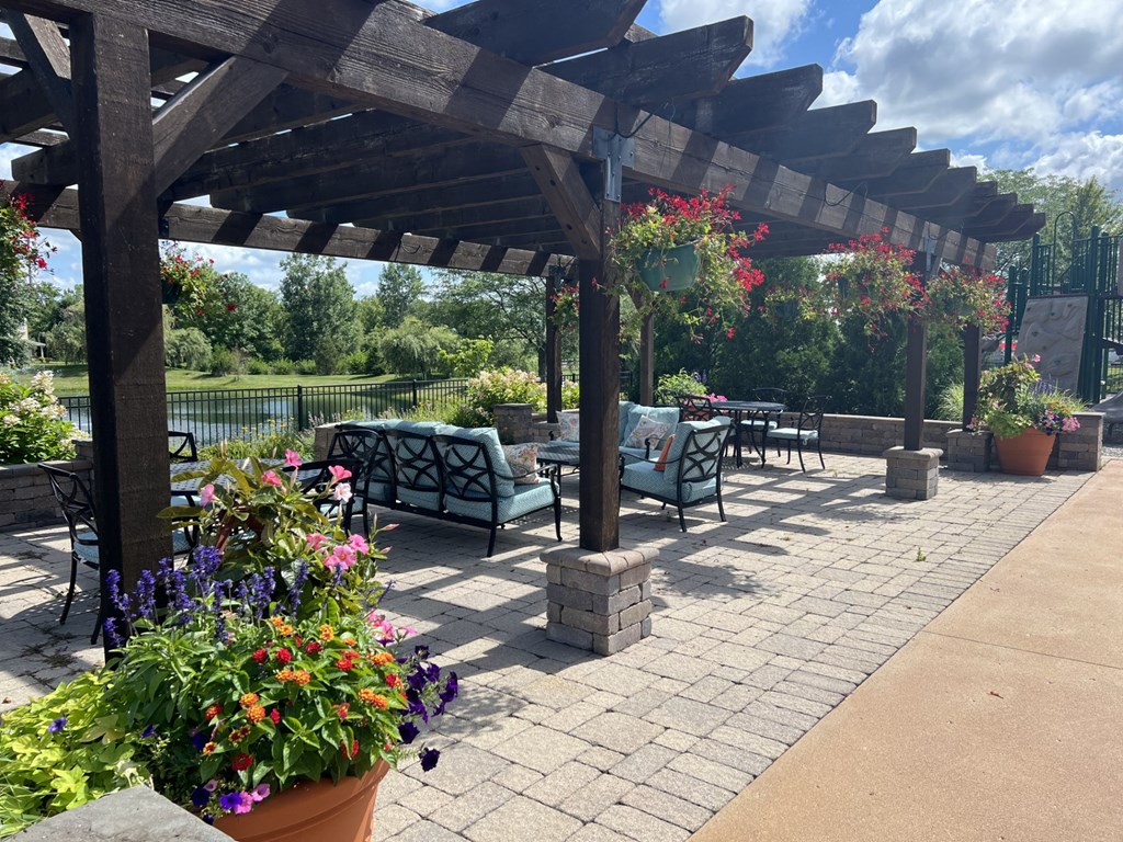 a covered patio with chairs and potted plants