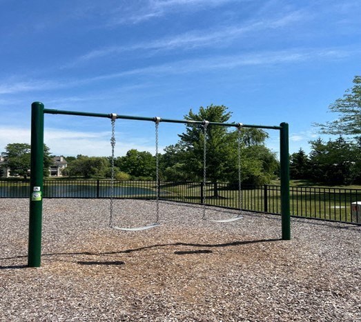 A playground with a swing set and a basketball hoop.