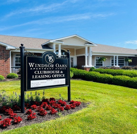 A sign for Windsor Oaks Apartment Homes and Clubhouse with leasing office.