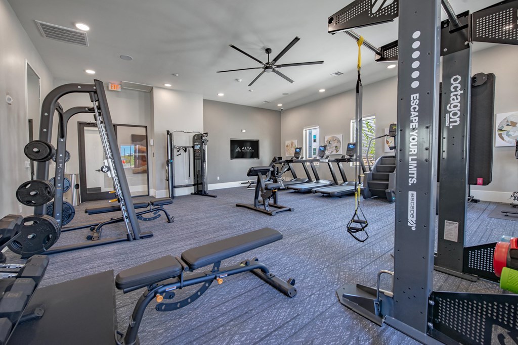 a gym with weights and cardio equipment and a tv