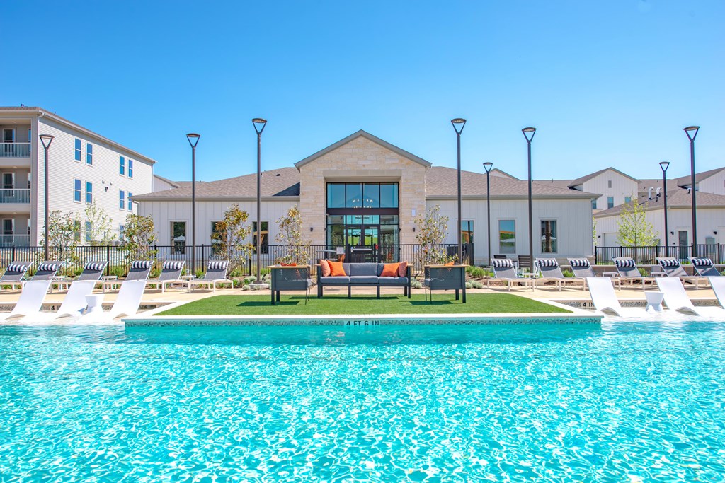 a swimming pool with lounge chairs and a building in the background