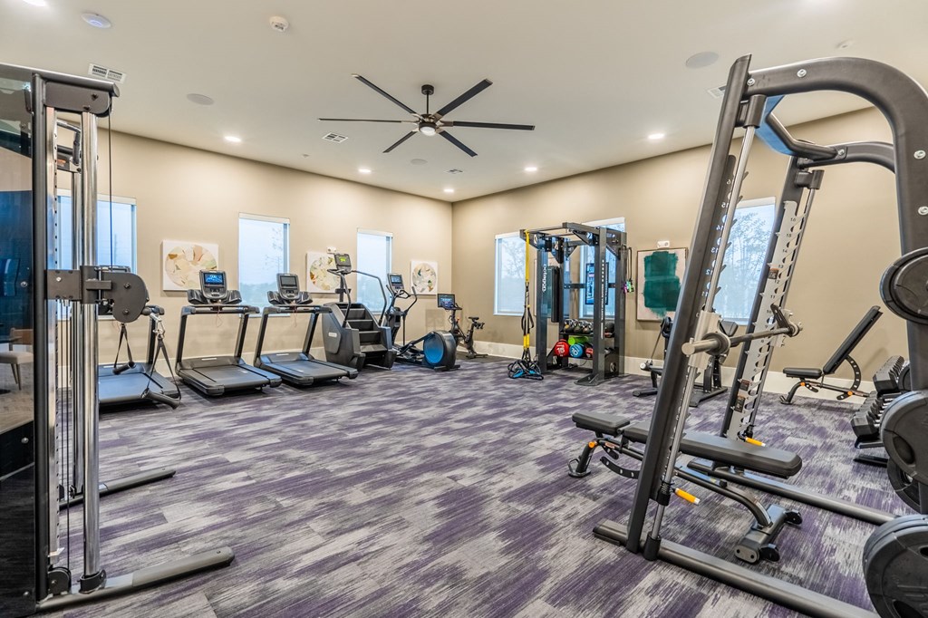a gym with cardio equipment and weights on the floor