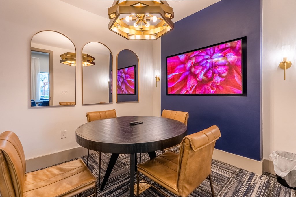 a conference room with a round table and chairs and a purple wall with three mirrors