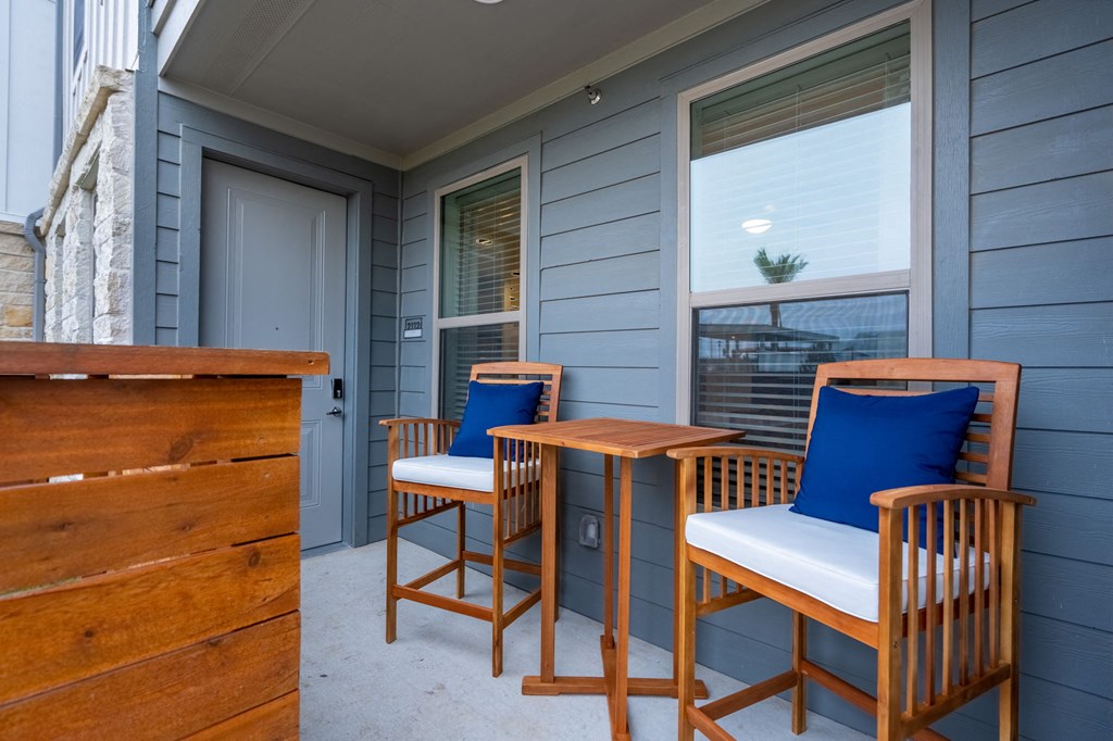 two chairs and a table on a porch with a door