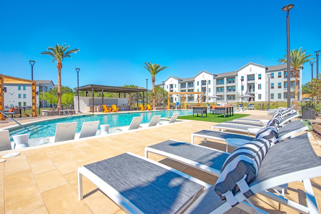 a pool with lounge chairs at the resort on a sunny day