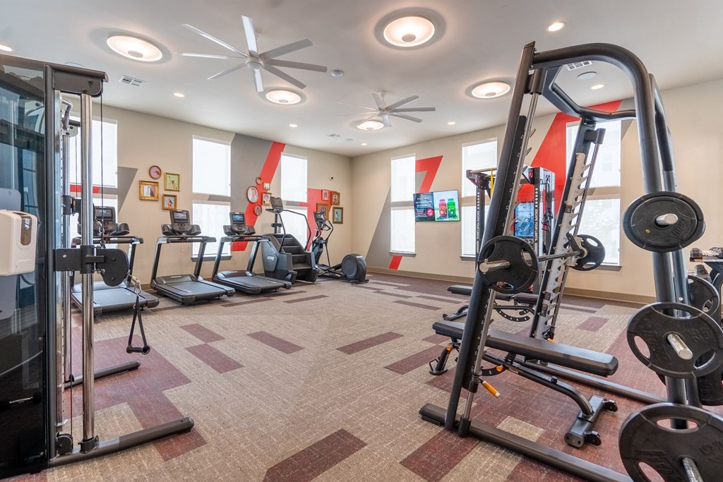 a large fitness room with exercise equipment and windows