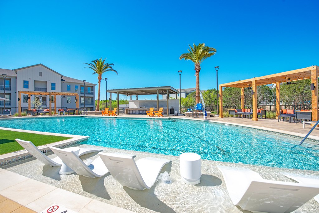 a swimming pool with chaise lounge chairs next to a building with palm trees