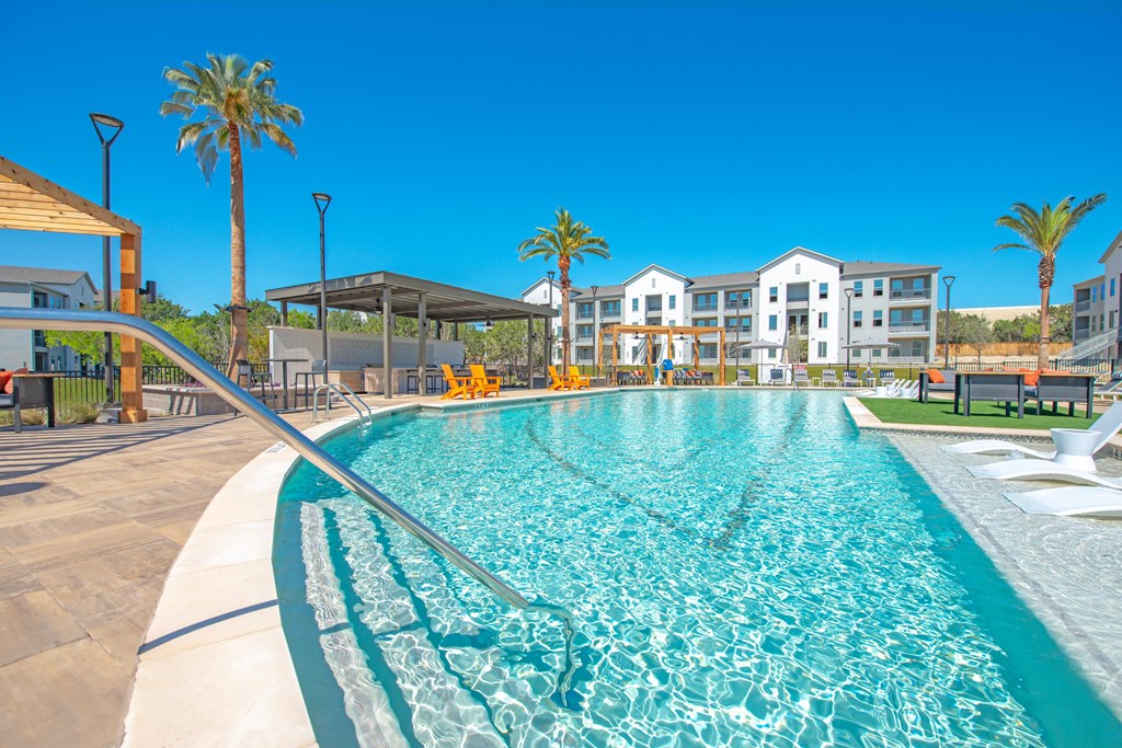 a swimming pool with palm trees and buildings in the background