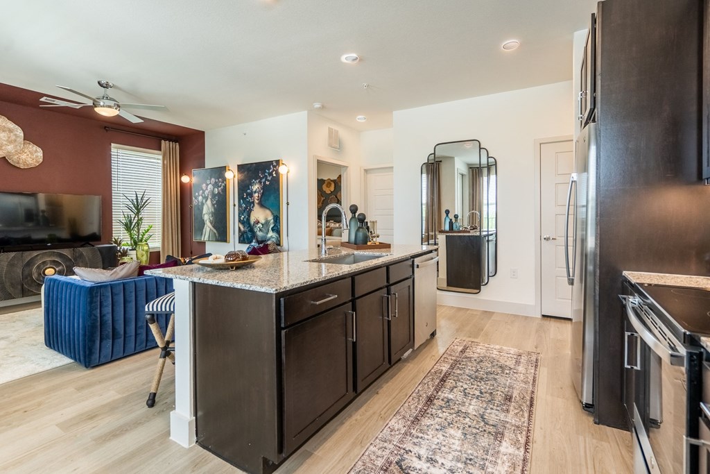 a kitchen with an island and a living room in the background