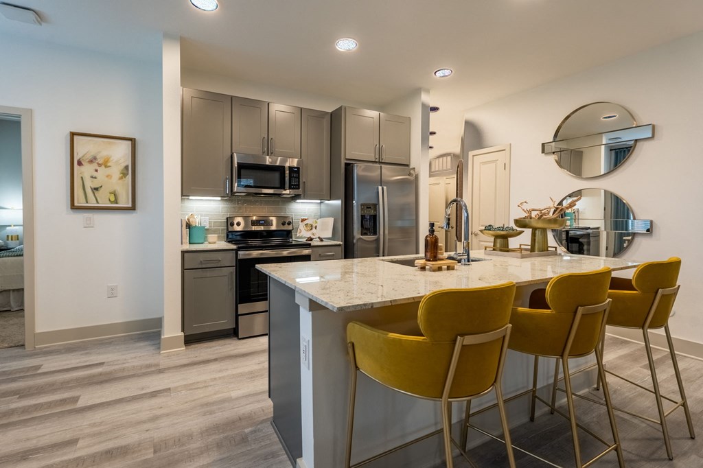 a kitchen with stainless steel appliances and a bar with yellow chairs