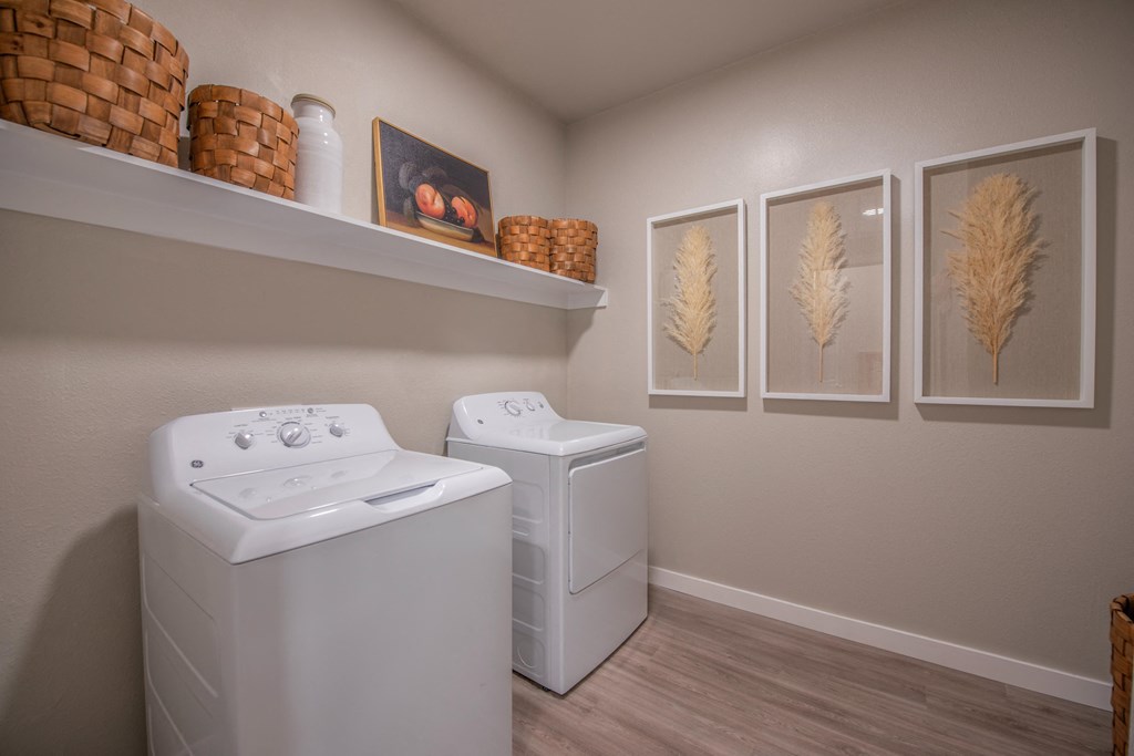 a laundry room with two washes and a dryer in it and some paintings