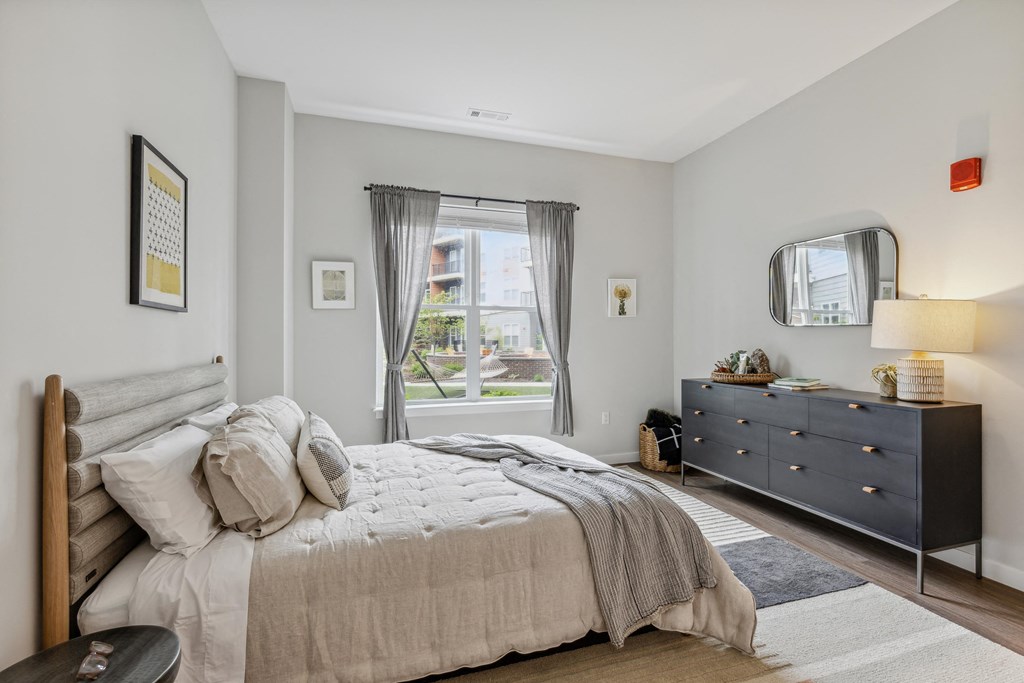 a bedroom with a bed and a dresser and a window