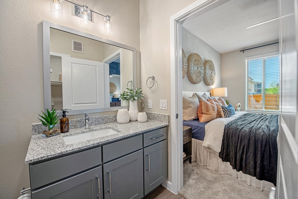 a bathroom with a sink and a mirror next to a bedroom