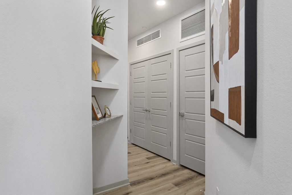 a hallway with white doors and white walls and wood floors