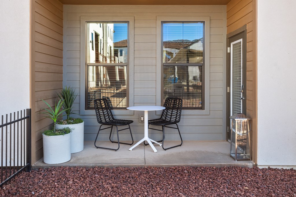 a patio with two chairs and a table on the side of a house
