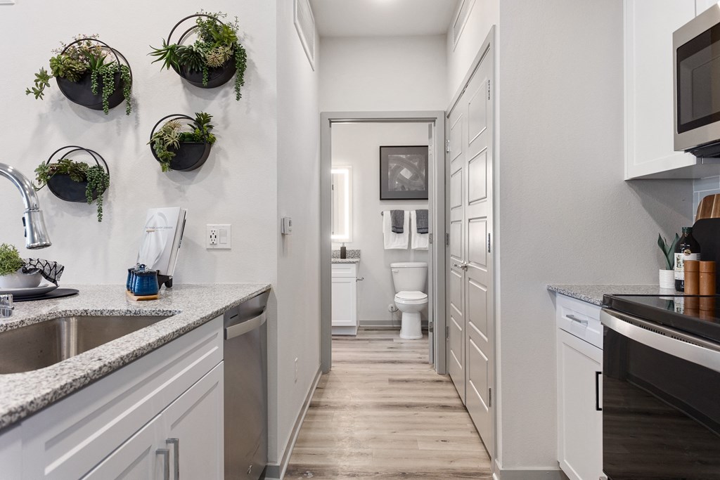 a spacious kitchen with white cabinets and a hallway to a bathroom