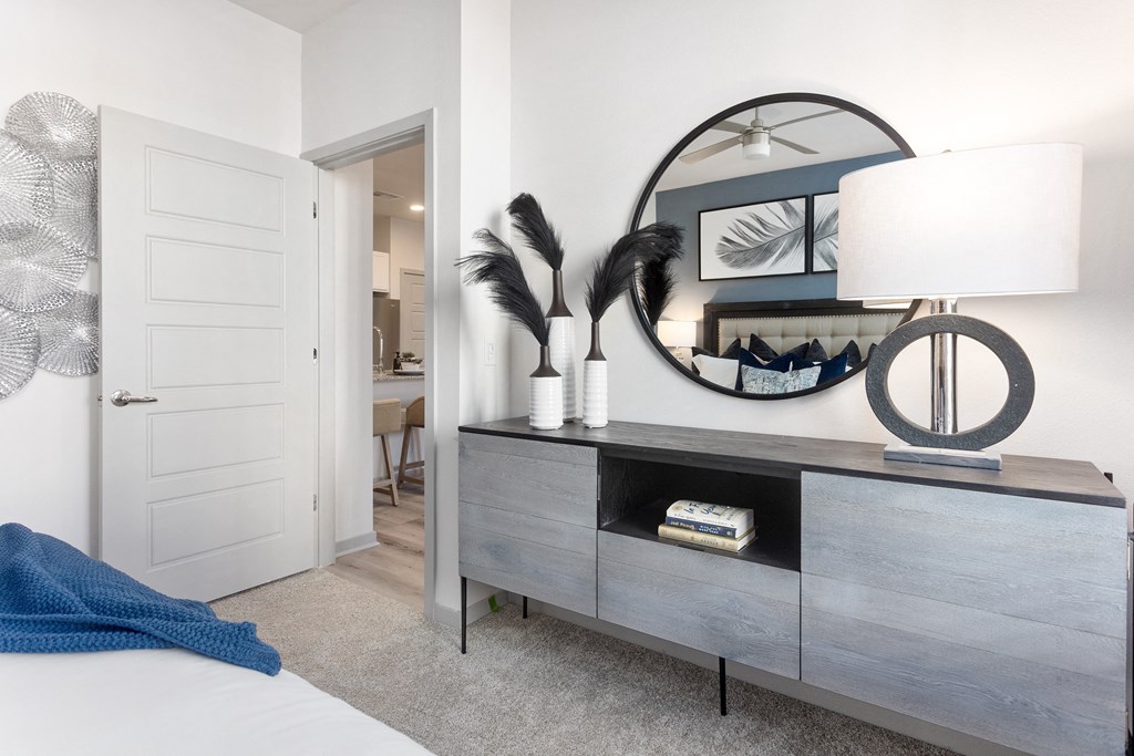 a bedroom with a dresser with a lamp and a mirror