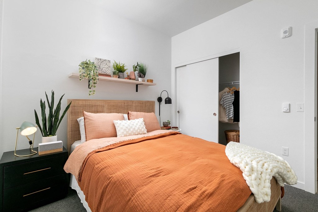 a bedroom with white walls and an orange bed