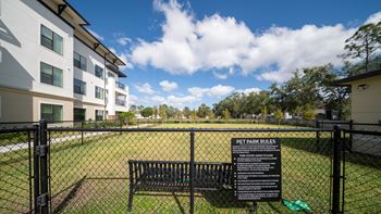 a park bench in front of a fenced in dog park