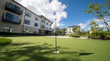a putting green with apartments in the background