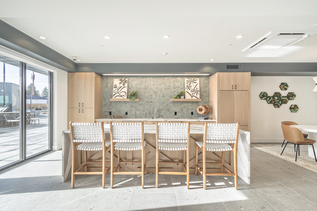 a kitchen with a bar and chairs in front of a window