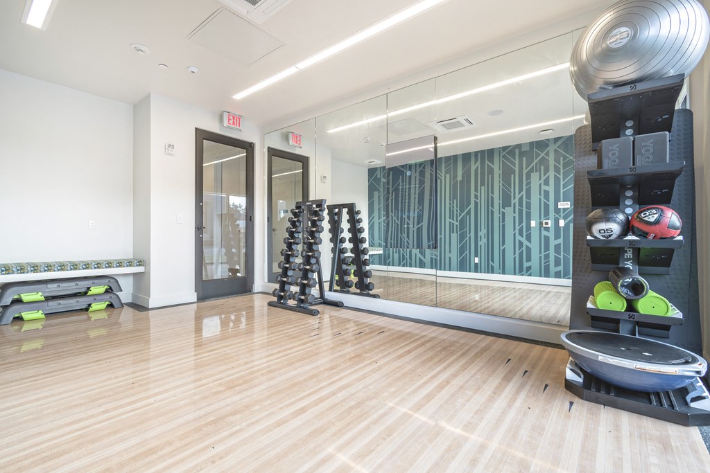 a fitness room with weights and a mirror on the wall