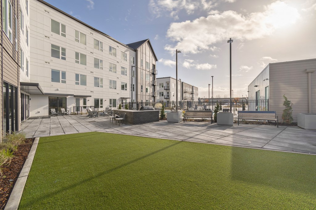 a courtyard with grass and benches in front of buildings