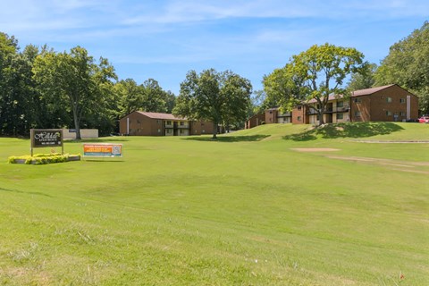 A Grassy Field With a Sign at Hilldale Apartments, Tennessee, 38128