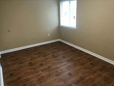 a empty room with wooden floors and a window