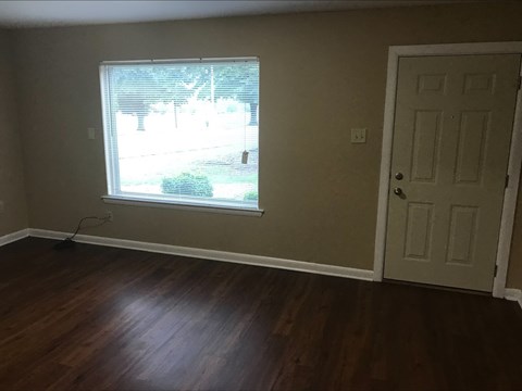 an empty room with a window and wooden floors
