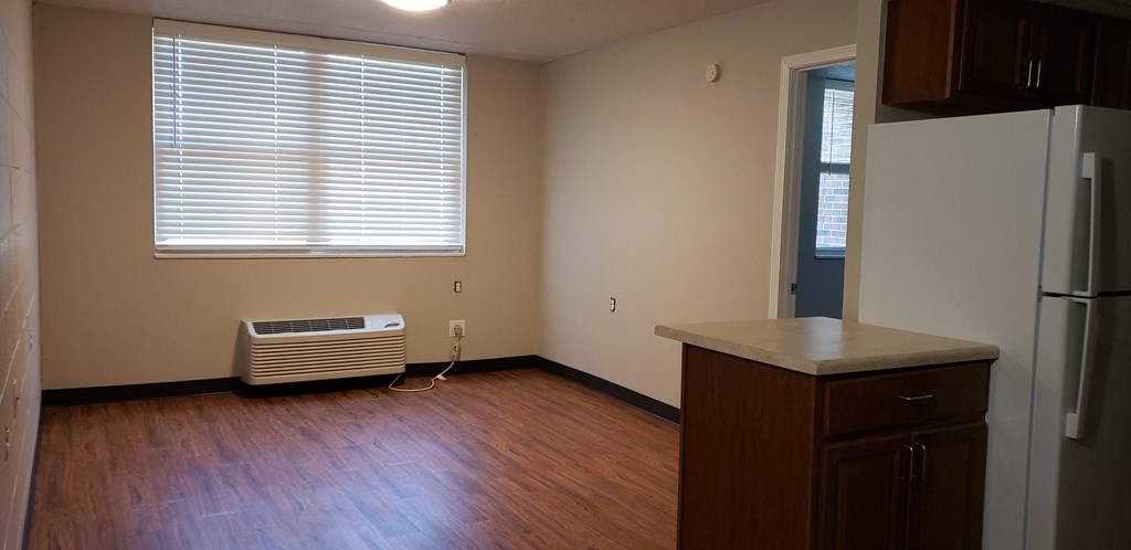 an empty kitchen with a refrigerator and a window