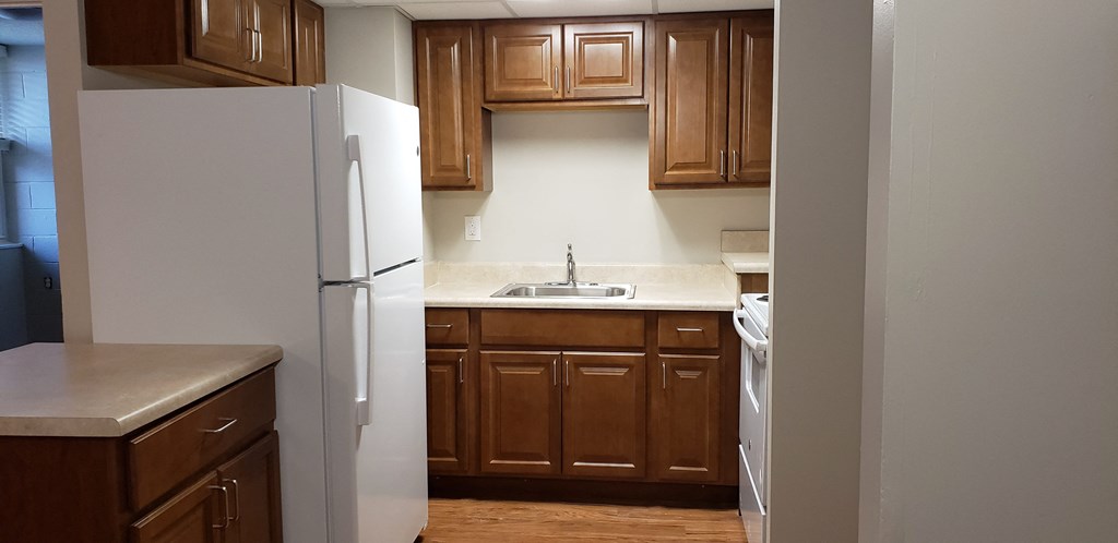 an empty kitchen with wooden cabinets and a white refrigerator