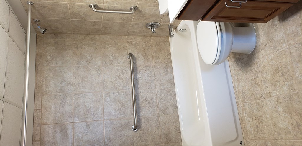 a white toilet in a bathroom with a rail next to it
