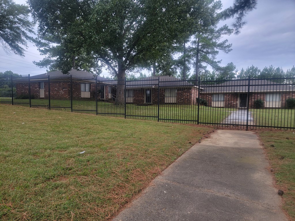 a yard in front of a house with a black fence