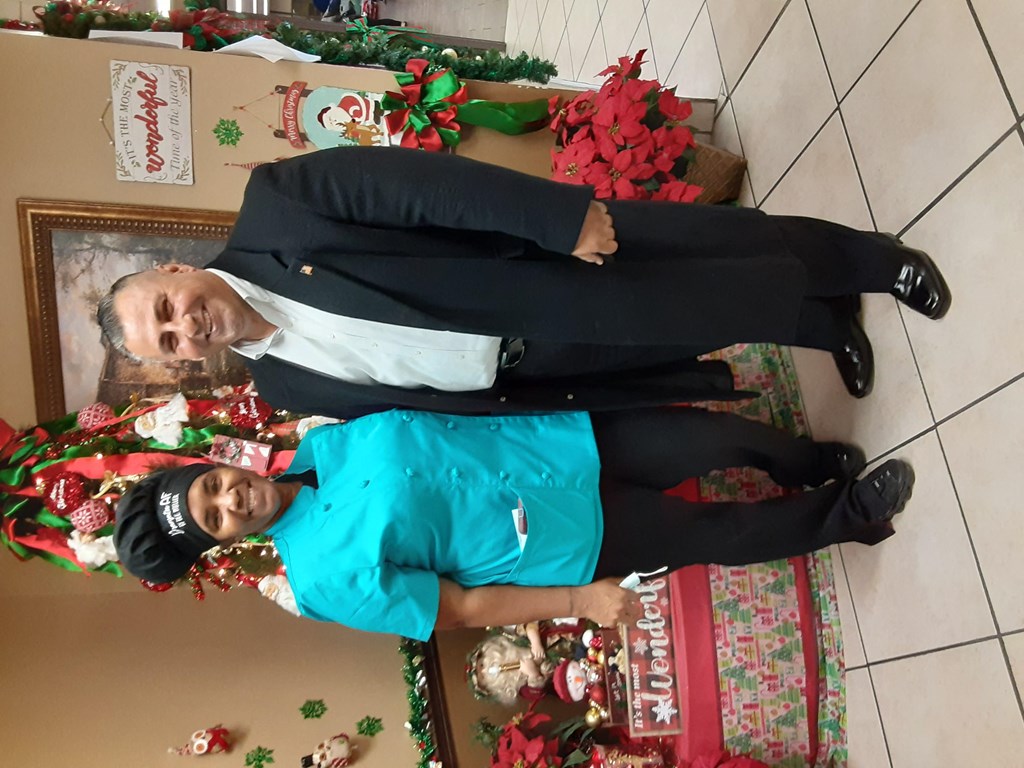 two people posing for a picture in front of a christmas tree