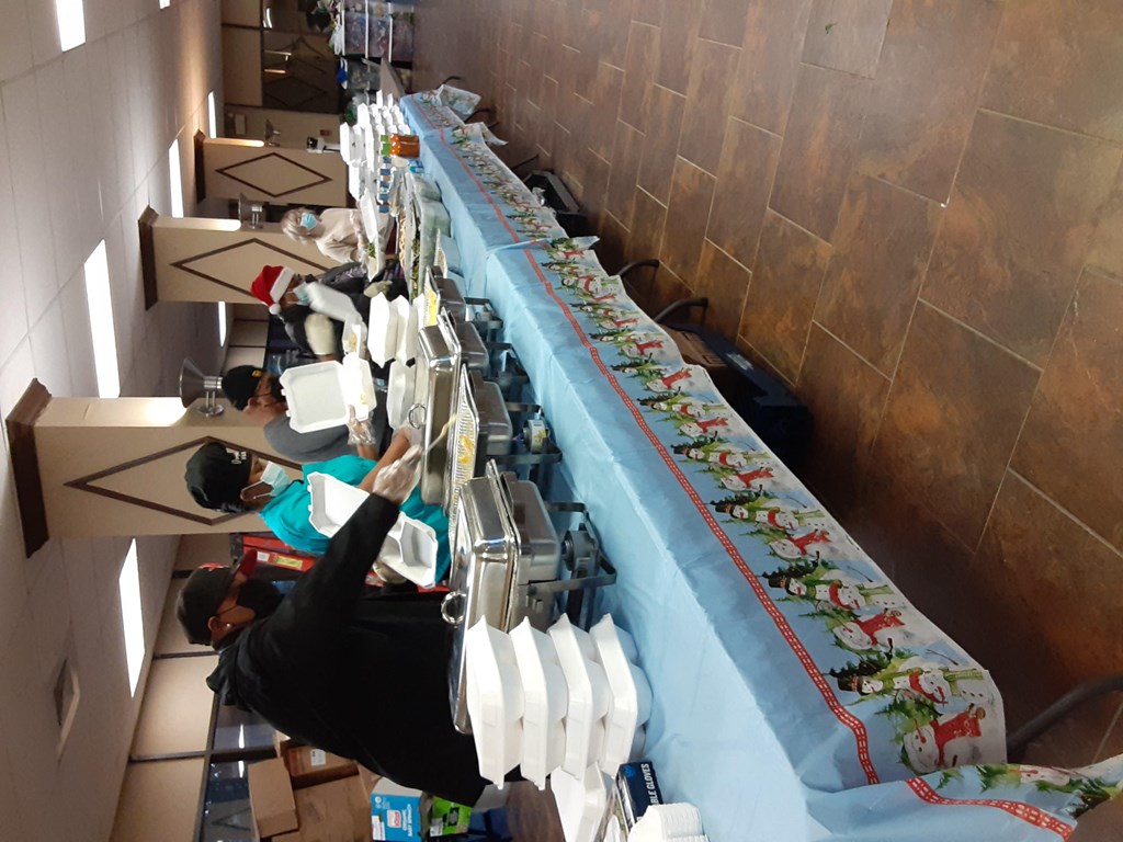 a line of sewing machines in a room with a long table with a blue curtain