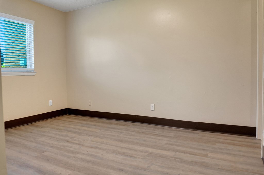 A room with wooden flooring and a window with blinds.