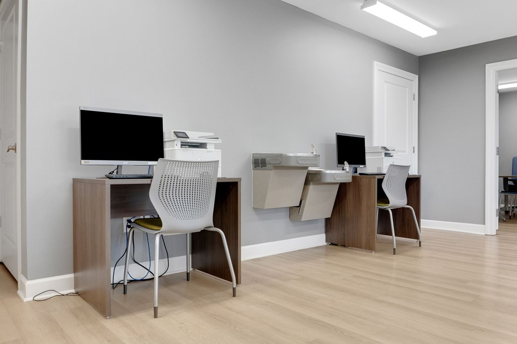 A room with two desks and chairs, one of which is white.