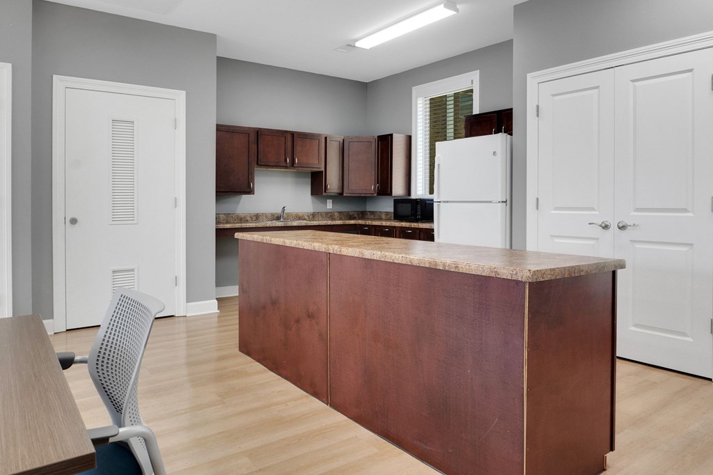 A kitchen with a brown island and white cabinets.