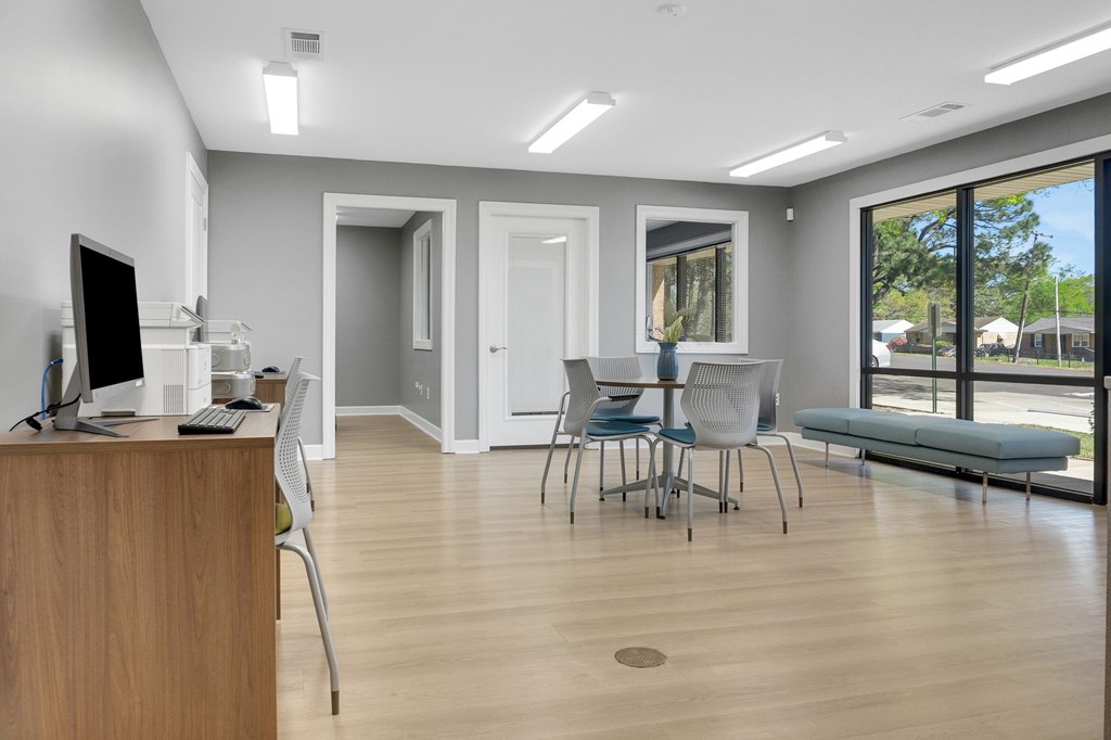 A room with a desk, chairs, and a window overlooking a street.