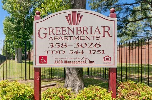 a sign for greenbar apartments in front of a fence