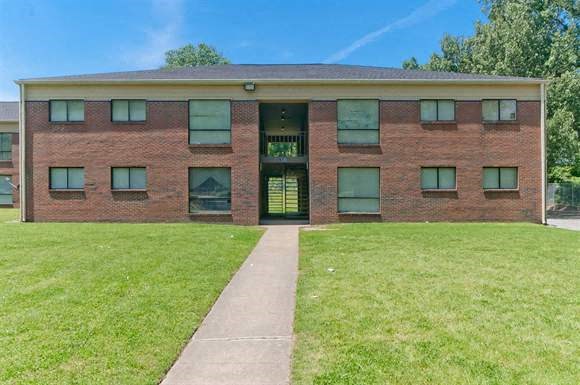 a brick building with green grass and a sidewalk
