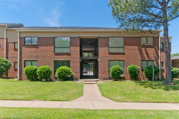 a brick apartment building with a sidewalk in front of it