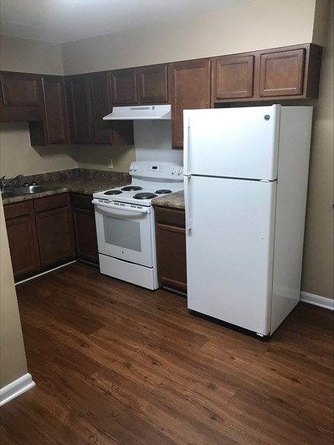 an empty kitchen with a white refrigerator and stove