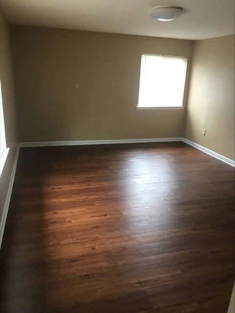 an empty living room with wooden floors and a window