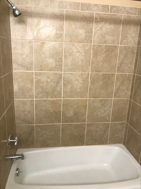 a white bath tub in a tiled bathroom