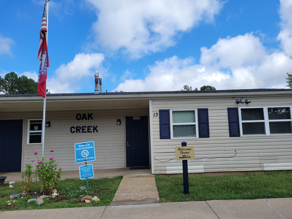a white building with an oak creek sign and an flag in front