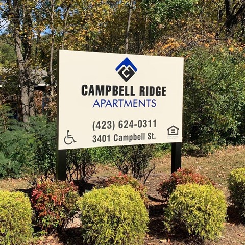 a sign apartments in front of bushes and trees