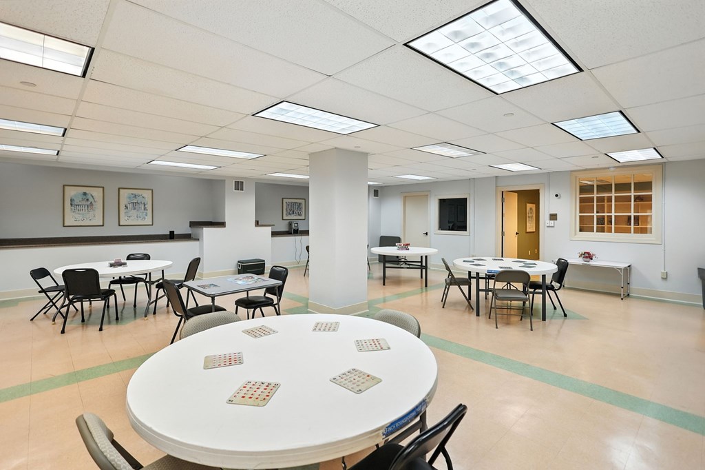 A conference room with tables and chairs and a white table in the center.