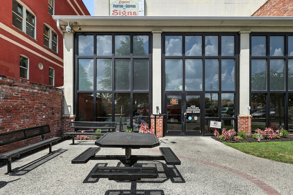 A black picnic table is in front of a glass door.